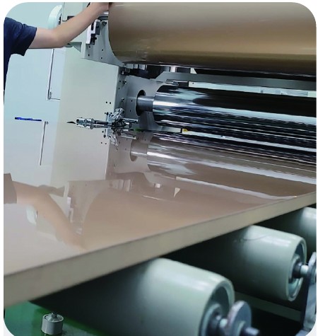 Flat lamination roller machine applying PUR hot melt adhesive to a panel surface